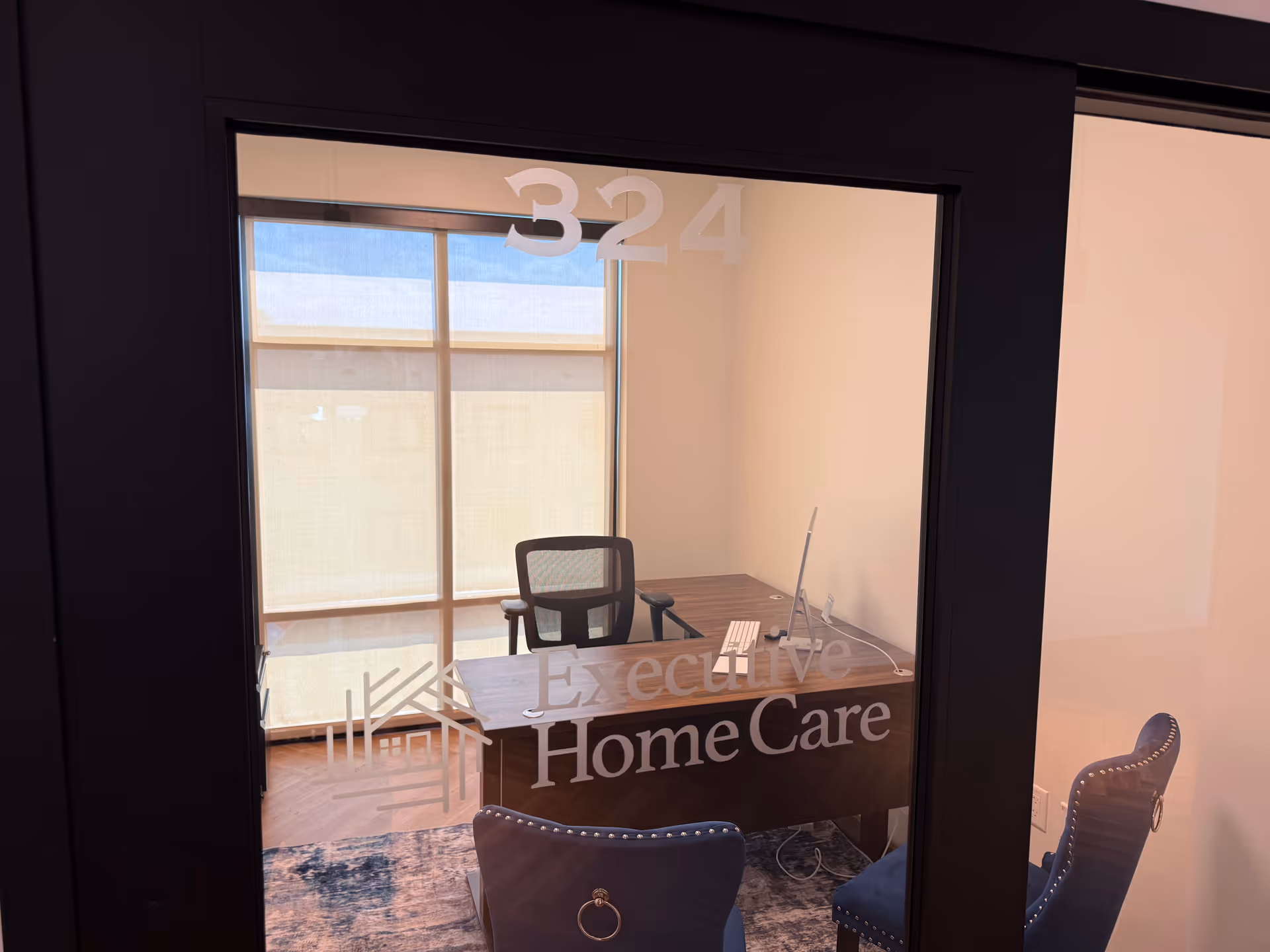 Office reception area with glass door, desk, chair, and branding for Executive HomeCare.