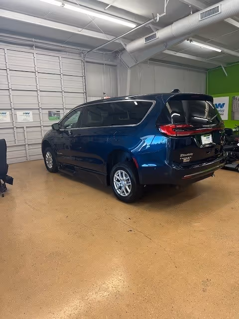 A blue minivan parked inside a garage with white doors and a green wall.