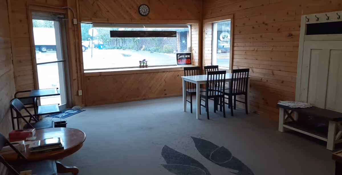 Wood-paneled interior with a dining table and chairs near a large front window.
