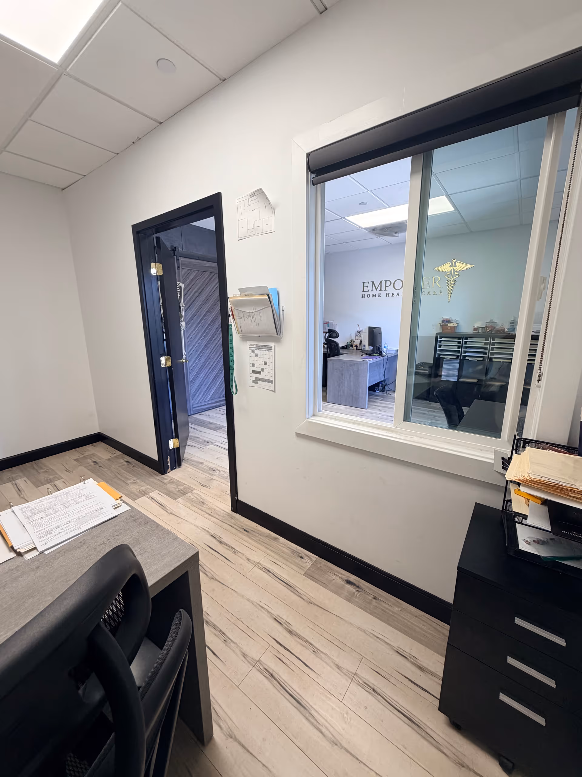 Office workspace inside Empower Home Health Care, with desk, chair, paperwork, and window.