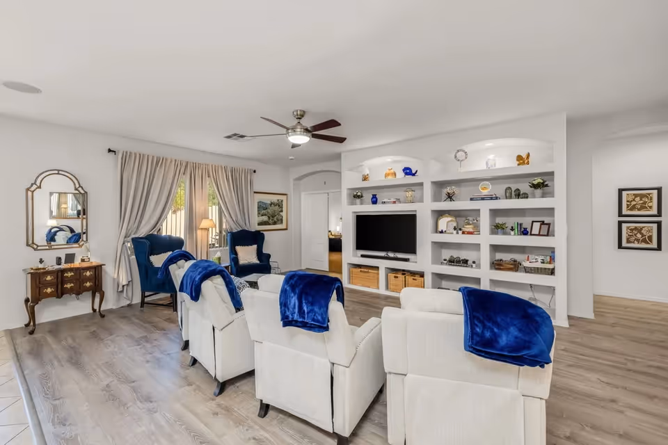 Sunnyvale Group living room with beige recliners, blue throws, and built-in shelves around a TV.