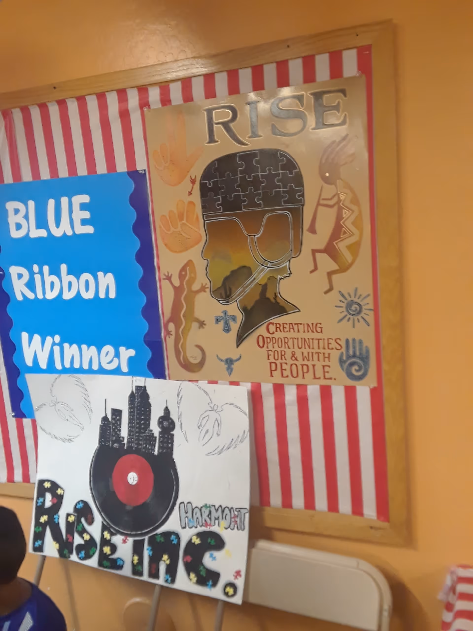 Colorful posters on a wall inside a senior living facility, featuring 'RISE' artwork and stripes.