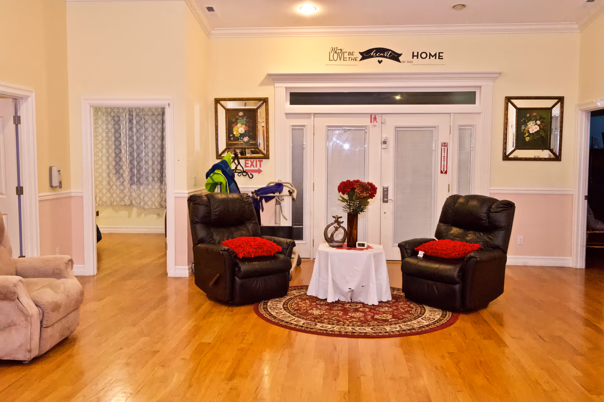 Two black leather recliners flank a small round table with red flowers in a cozy lobby.