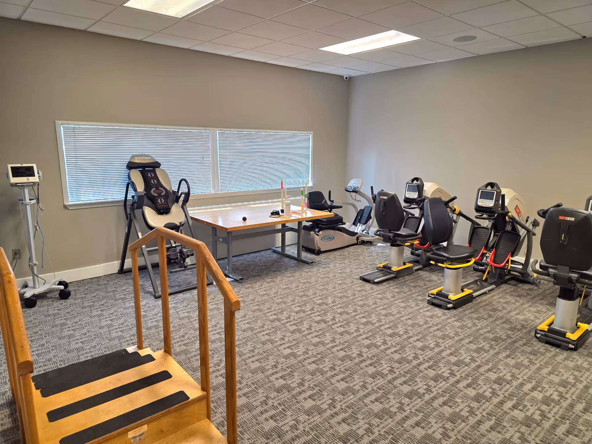 Indoor exercise room with multiple stationary bikes and a wooden stair platform.