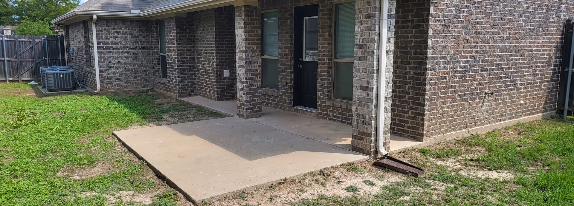 Brick senior living facility exterior with a concrete patio and doorway.