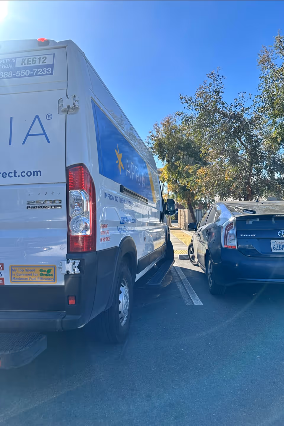 Apria Healthcare delivery van parked beside a blue car in a parking lot.