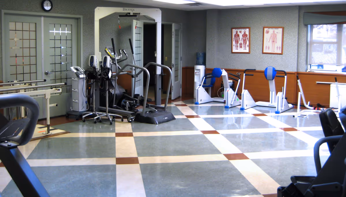 Interior rehabilitation gym with exercise machines and anatomy posters on the walls.