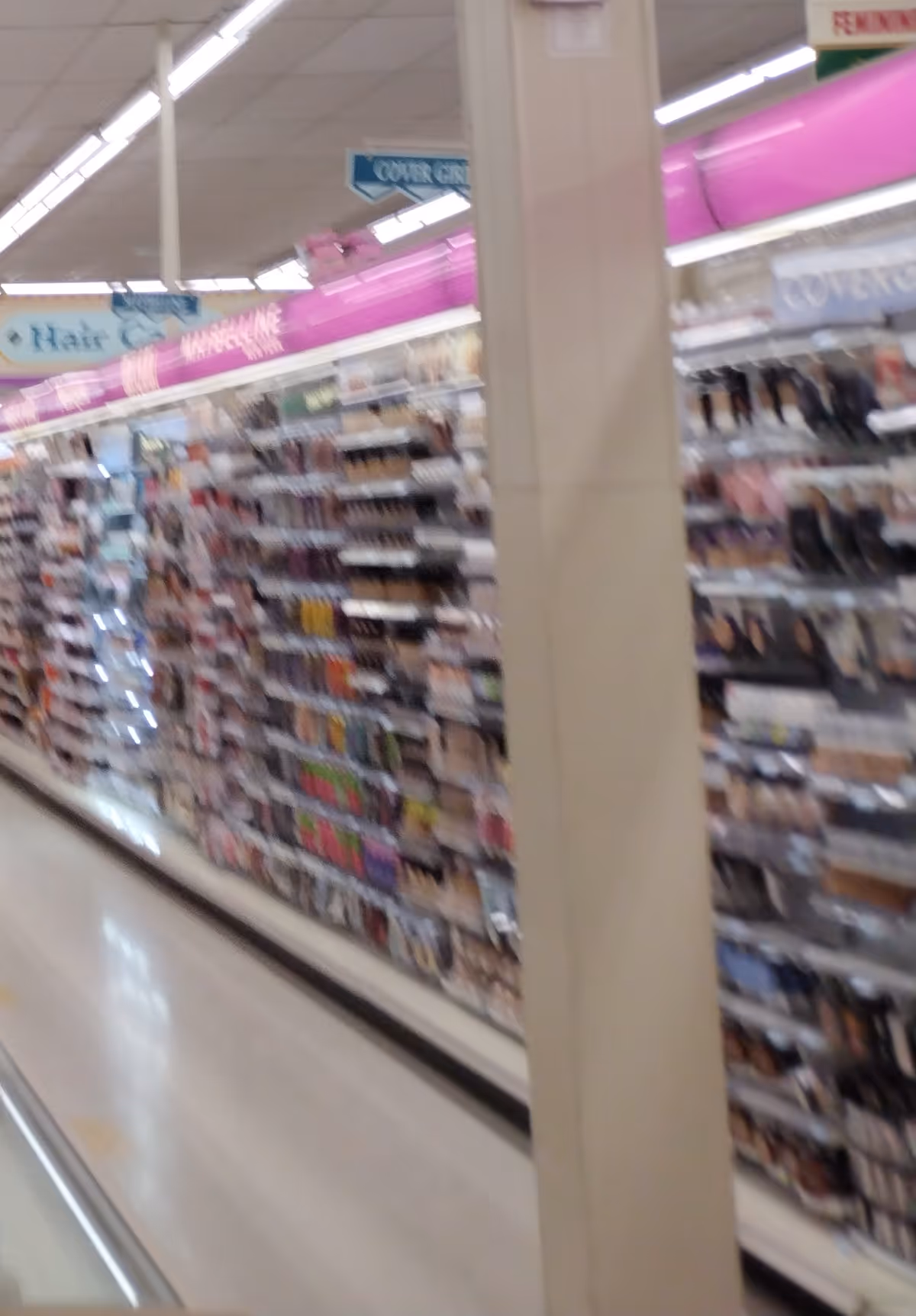 Blurred view of Discount Drug Mart aisles with cosmetics on shelves