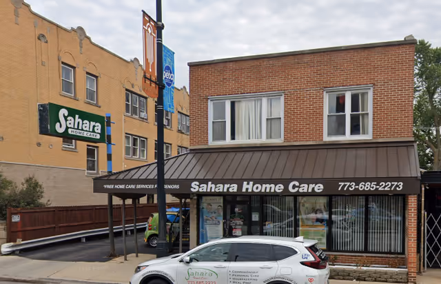 Exterior view of Sahara Home Care storefront with awning, brick facade, and a white car parked.