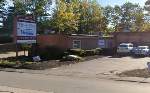 Exterior view of a Senior Helpers facility with a sign and parked cars.