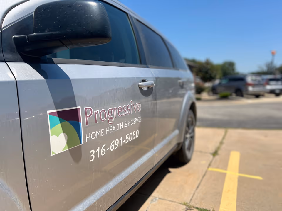 Side view of a Progressive Home Health & Hospice branded vehicle parked in a lot.