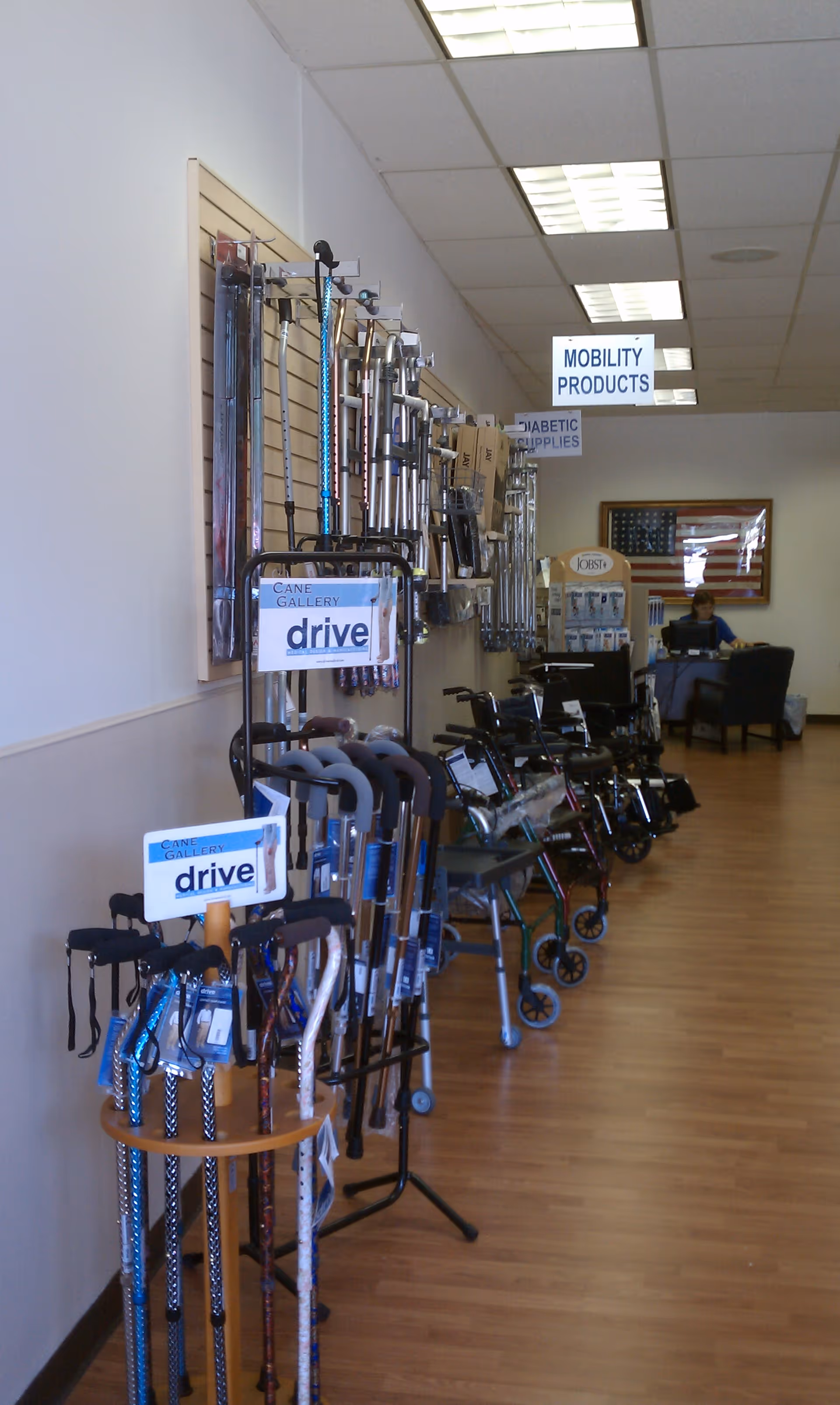 A hallway showroom displaying canes, walkers, and mobility aids along a wall.