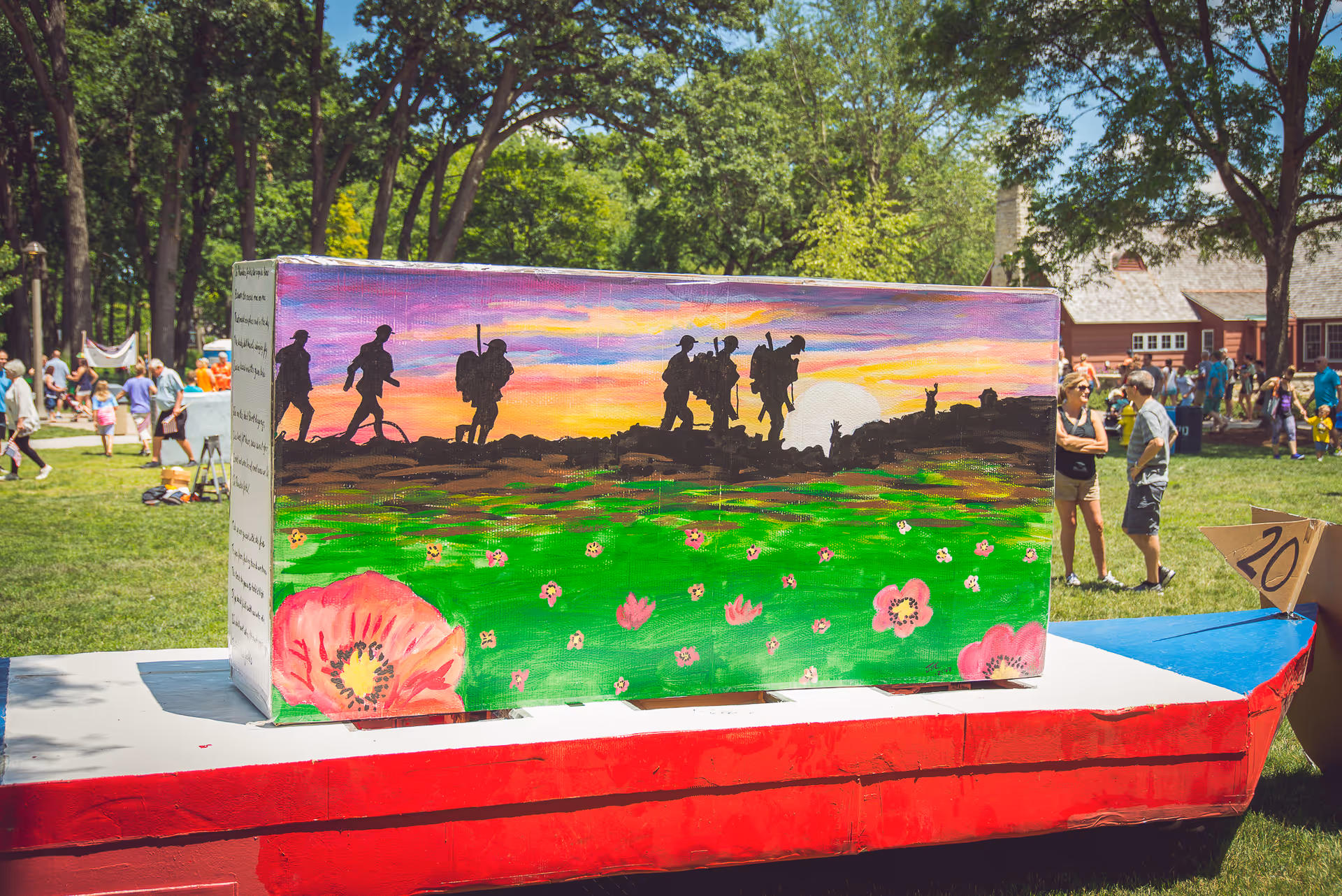 Colorful painted box on a red platform at an outdoor community event.