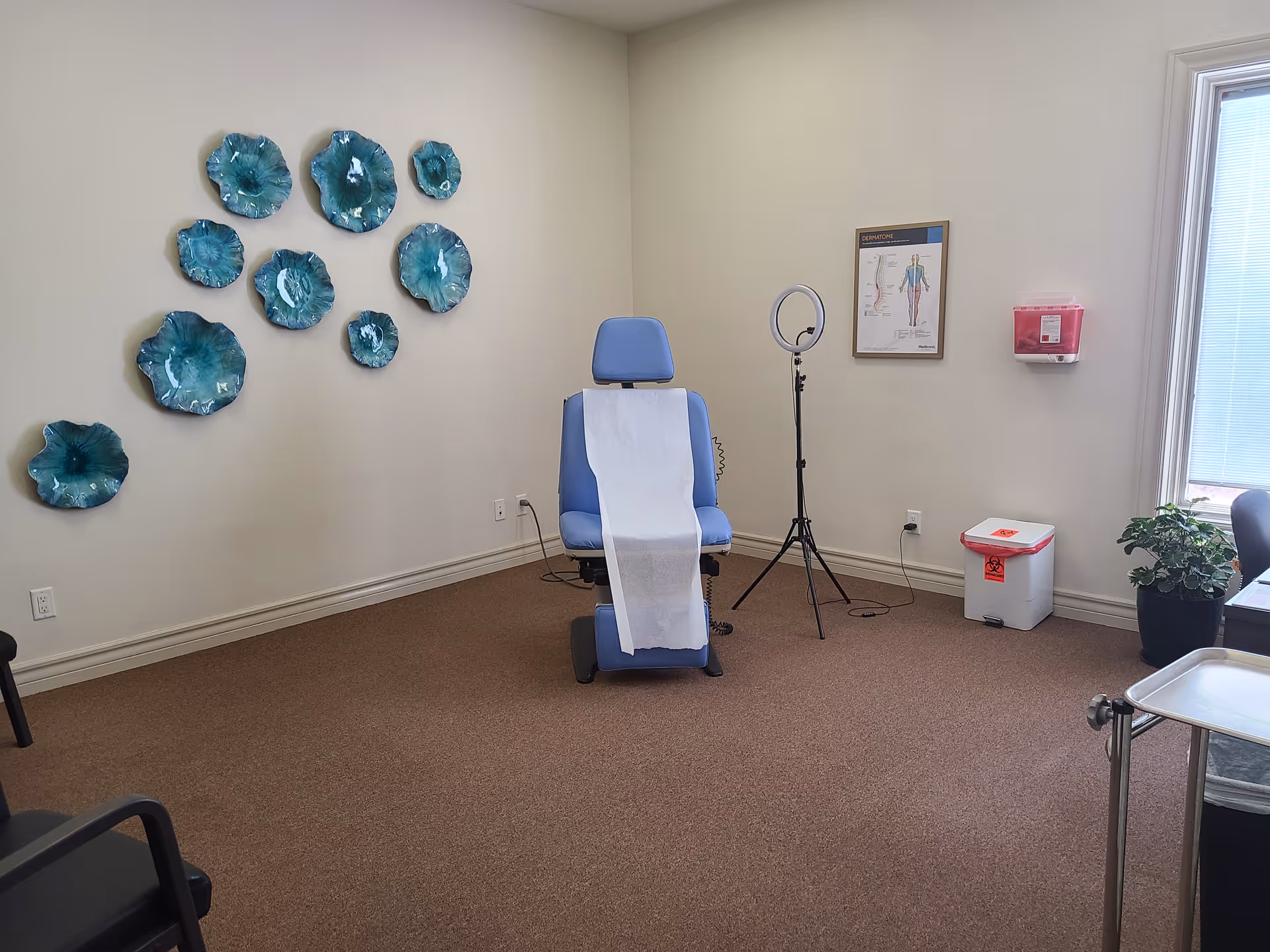 Blue medical chair with paper drape in a clean treatment room.