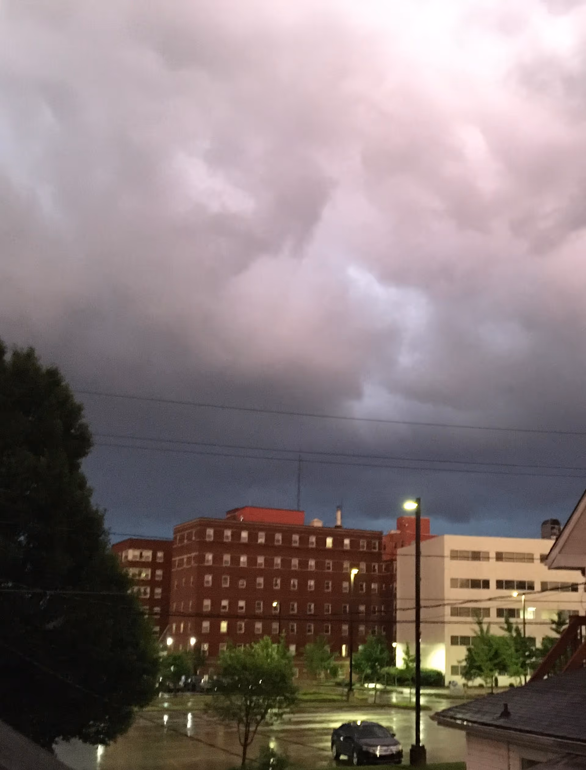 Stormy sky over hospital campus with brick buildings and wet streets at dusk.