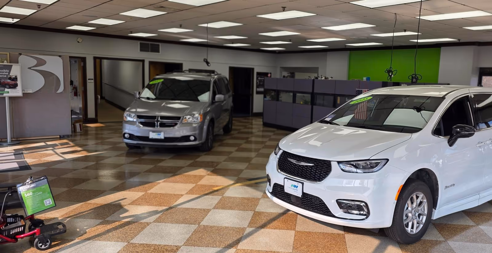 White van and gray van inside MobilityWorks showroom on checkered tile floor