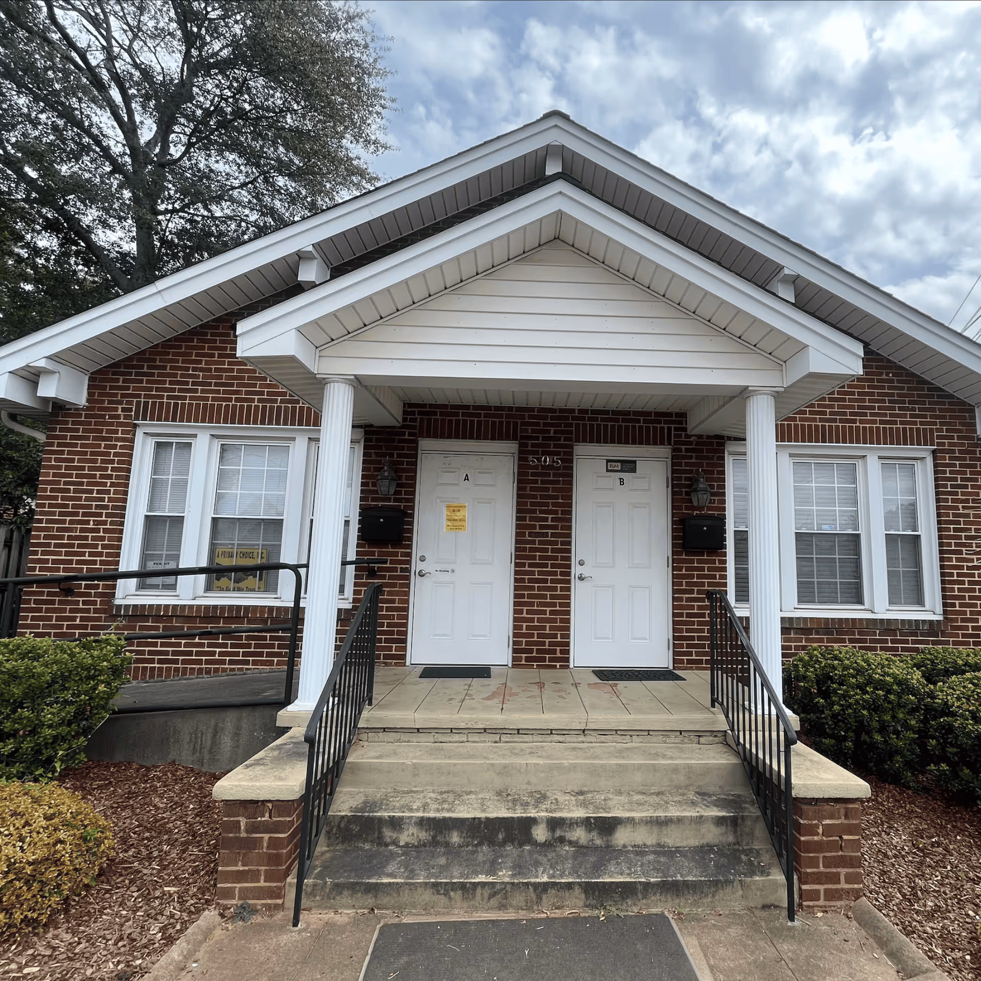 Brick single-story facility entrance with two white doors labeled A and B under a gabled porch.