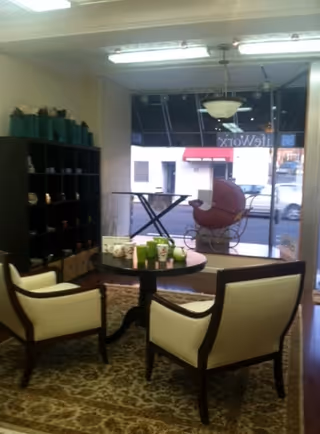 Lobby living room with two beige armchairs around a round coffee table and a shelving unit.