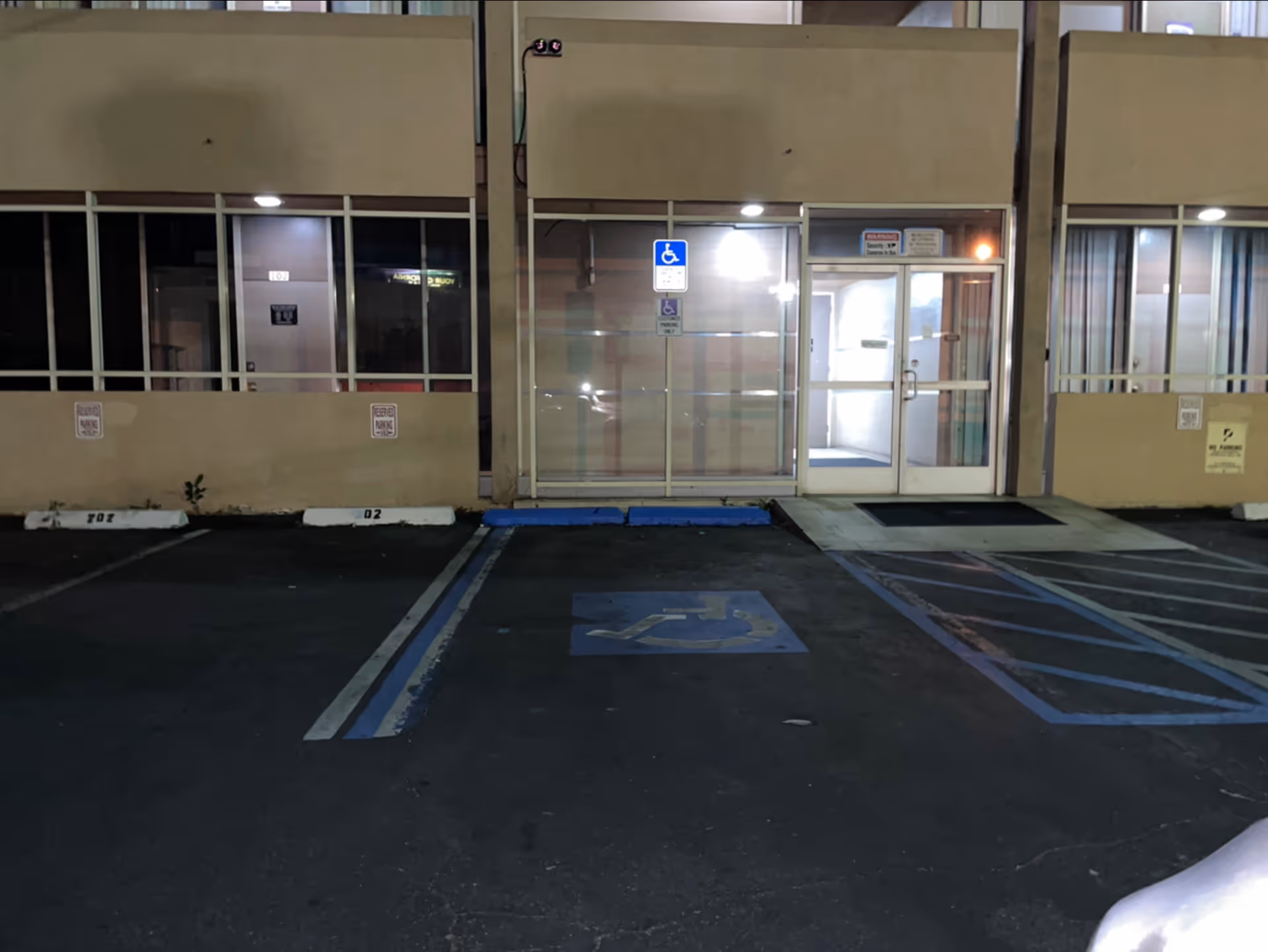 Exterior of a hospice facility with glass entrance doors and handicap parking.