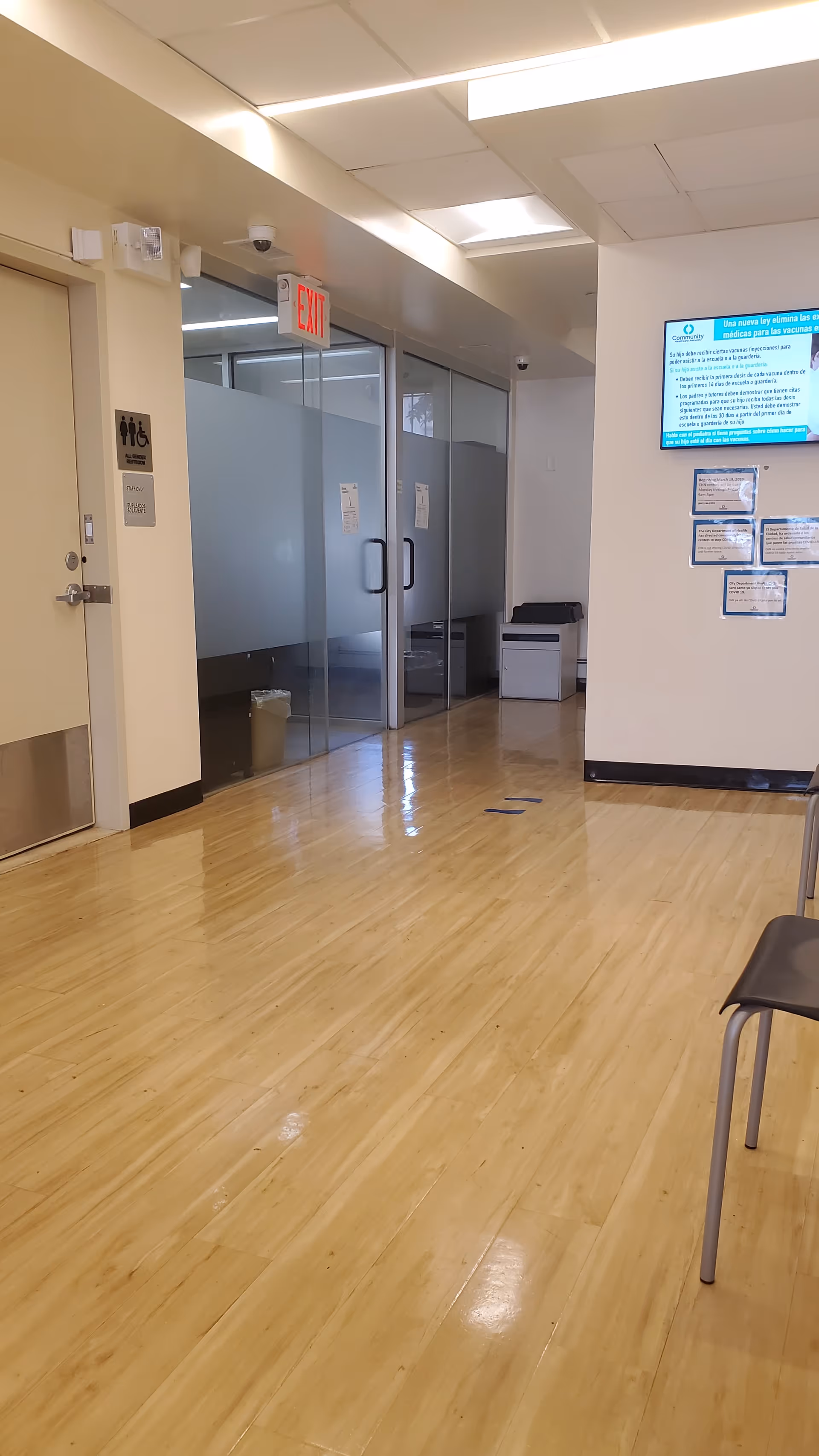 Long hallway inside a senior facility with glass doors, signage, and wooden flooring.