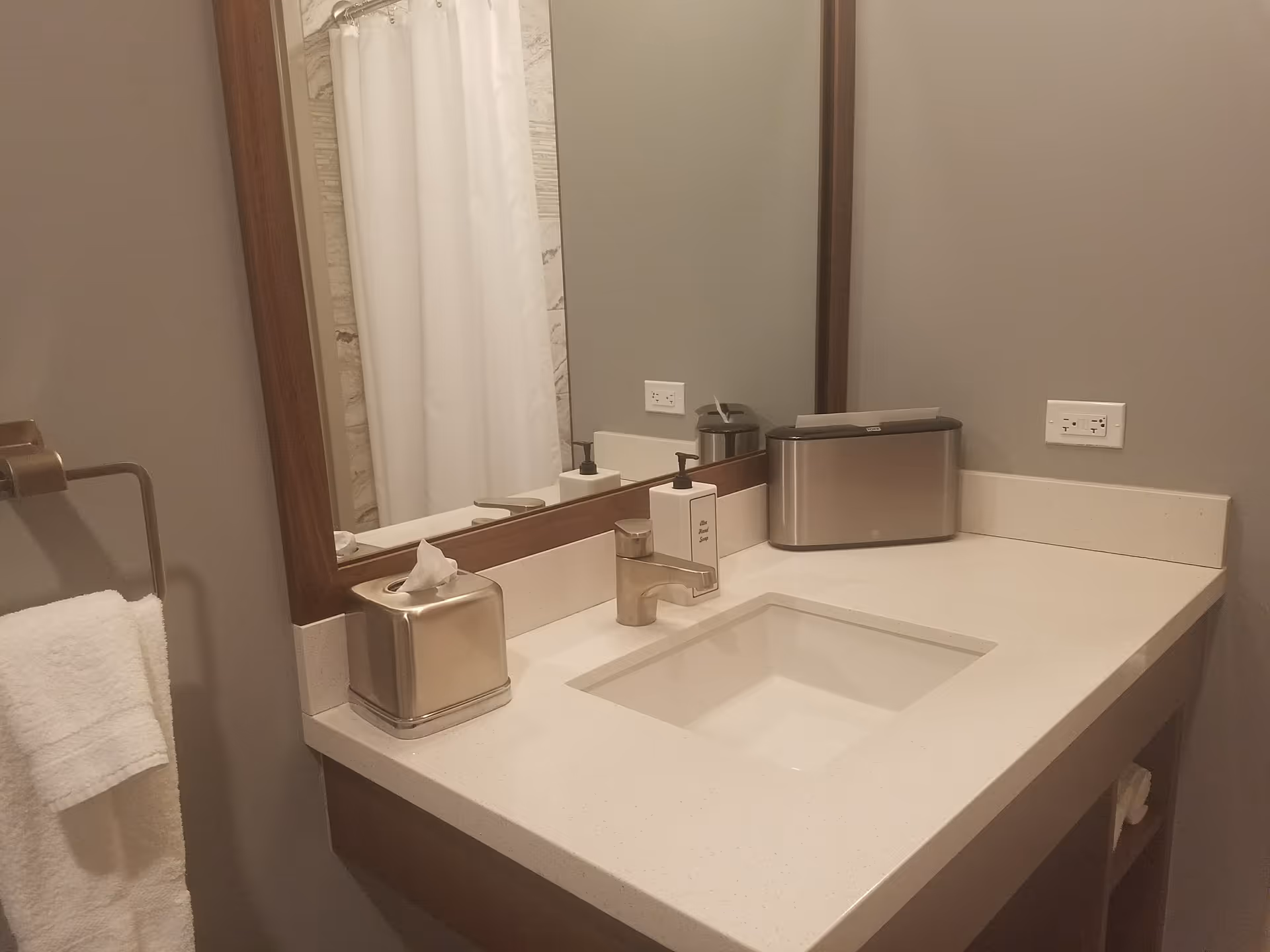 Bathroom vanity with sink, mirror, tissue box, towel, and shower curtain.