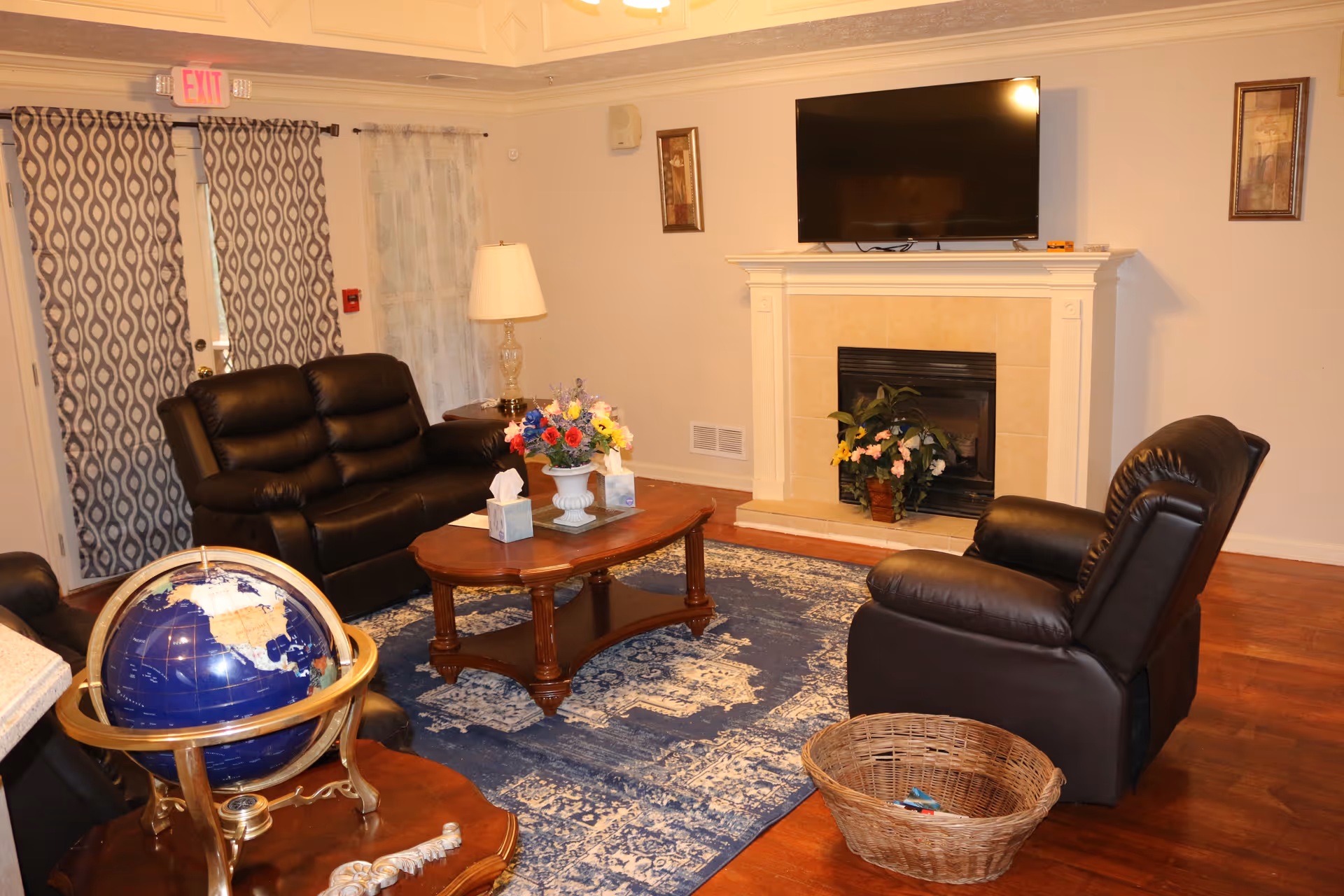 Cozy living room in a senior facility with leather seating and a fireplace.
