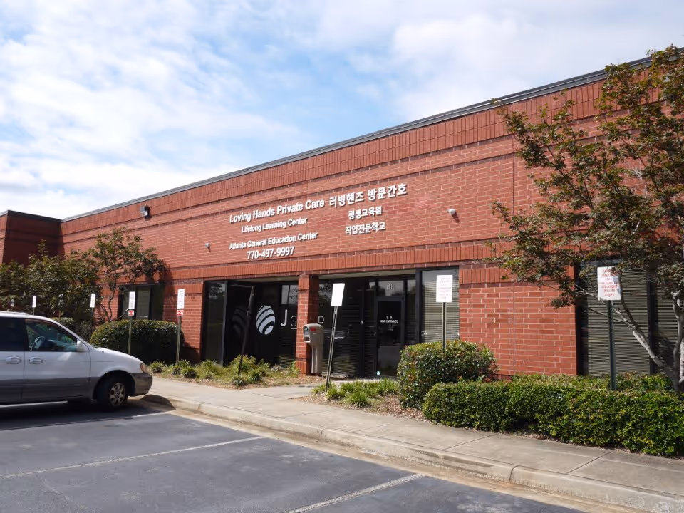 Brick building exterior with Loving Hands Private Care signage and a parked car.