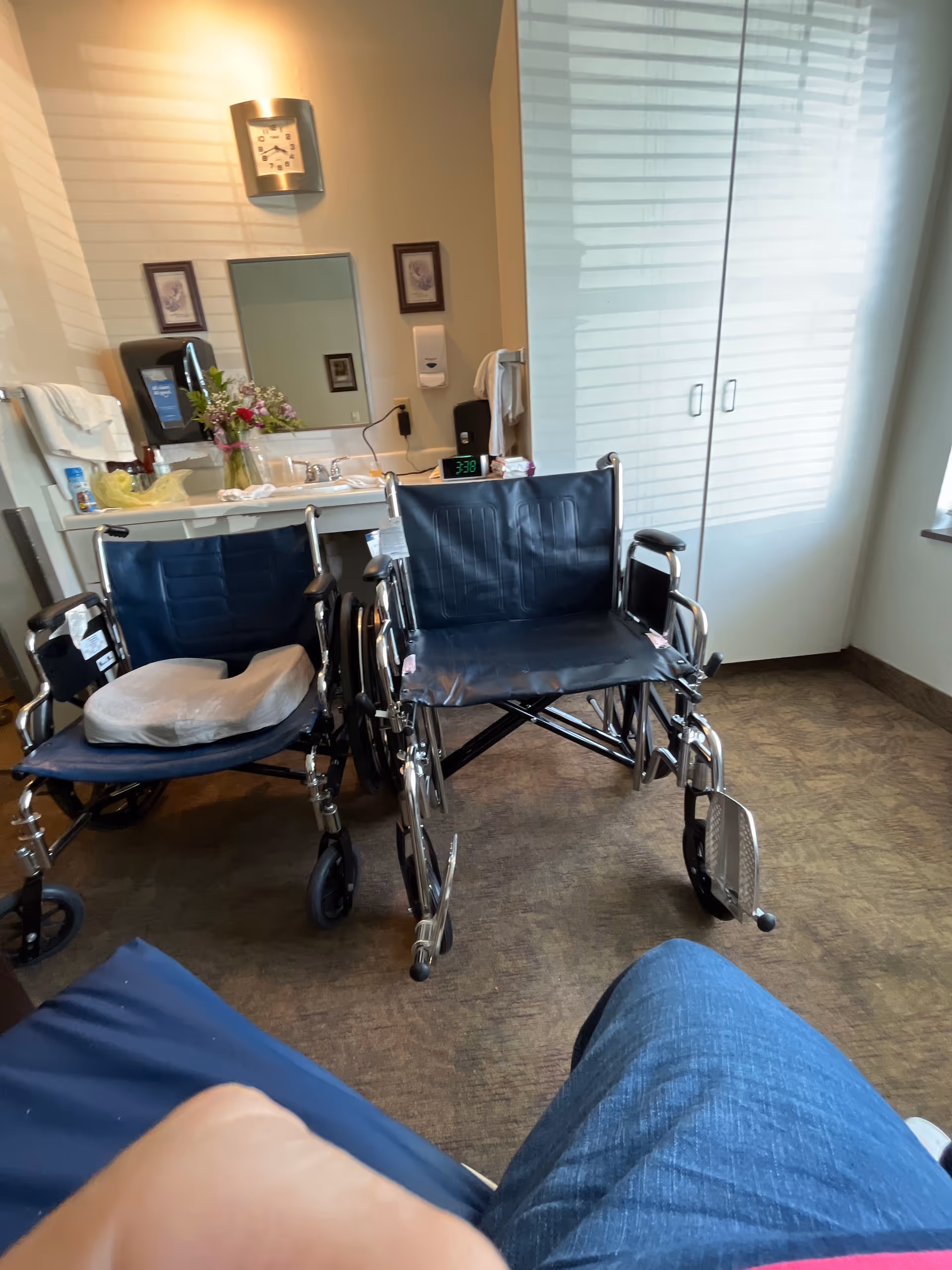 Two wheelchairs are parked near a sink and mirror in a care room.