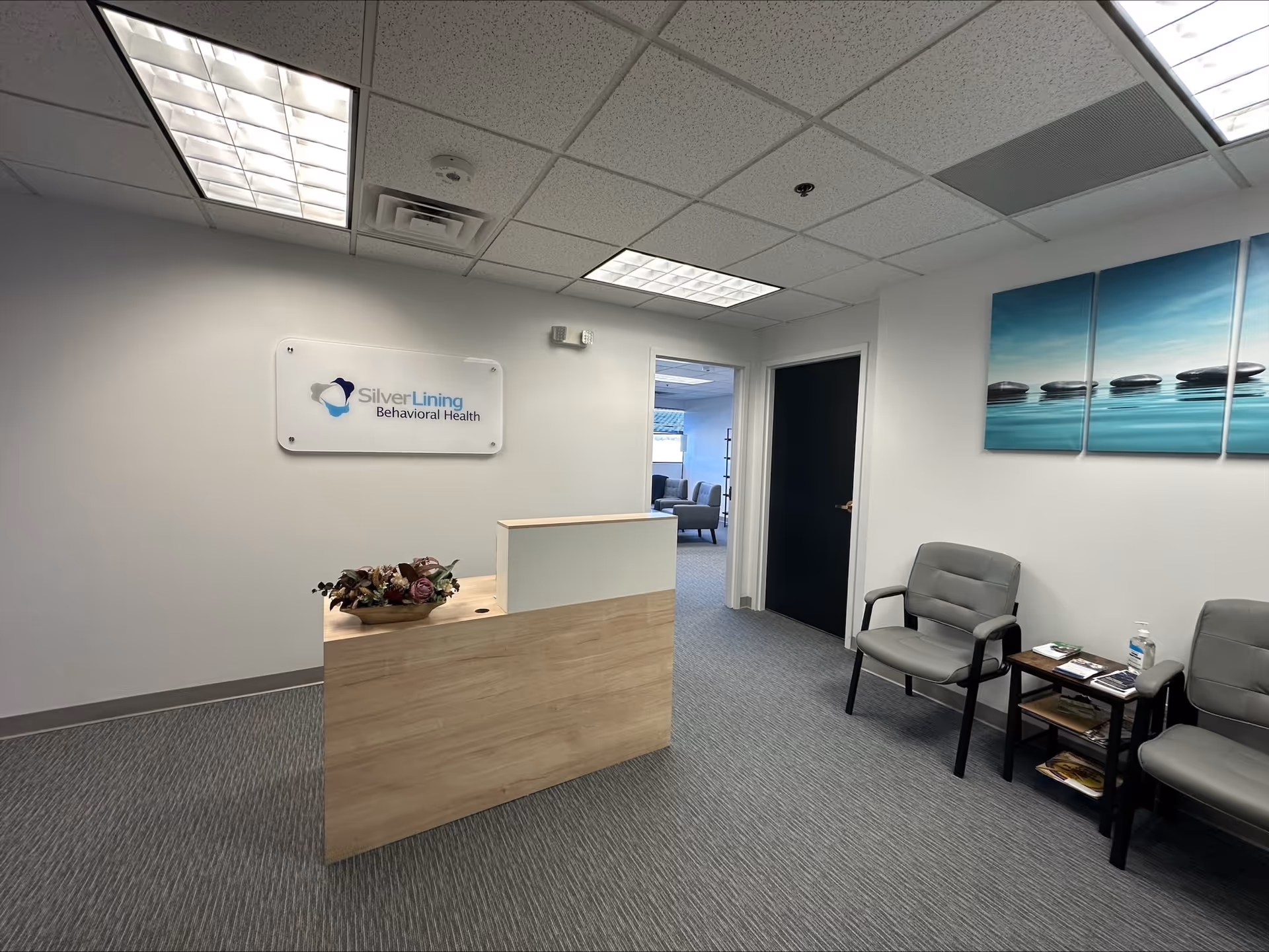 Reception desk in a clinic lobby with seating and a Silver Lining Behavioral Health sign.
