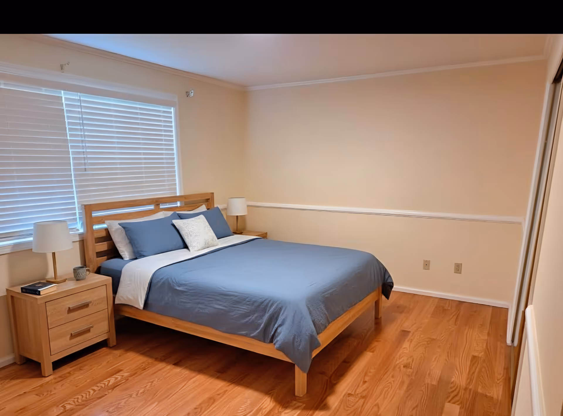 A tidy bedroom with blue bedding, wooden bed frame, and two nightstands.