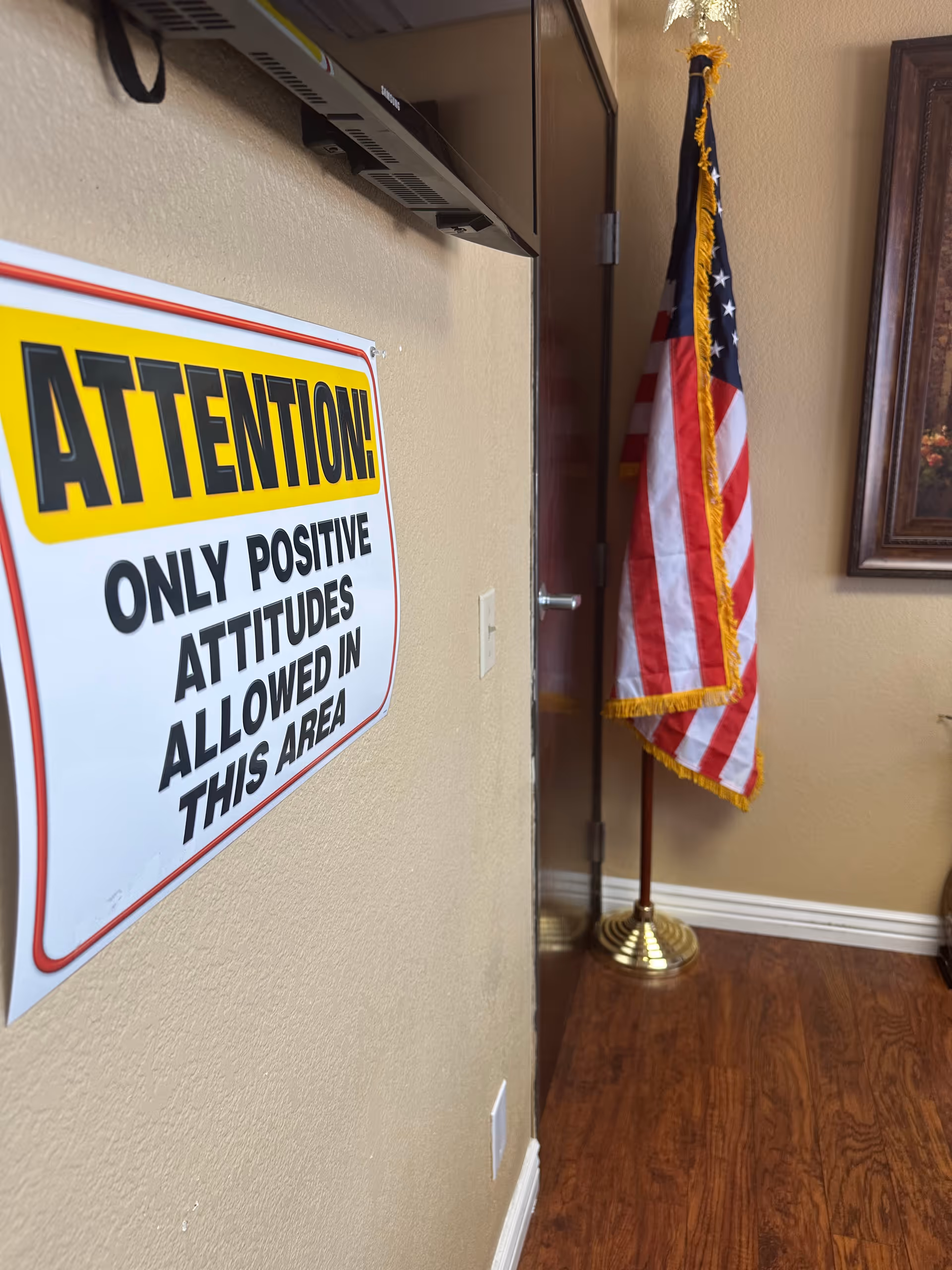 Hallway interior with a bold ATTENTION sign and an American flag near a door.