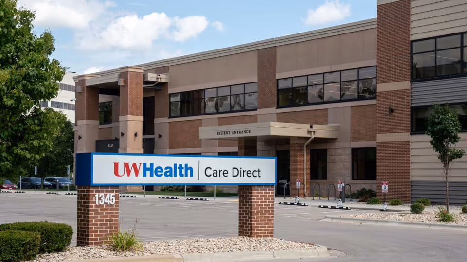 Exterior view of UW Health Care Direct facility with brick entrance and parking lot.