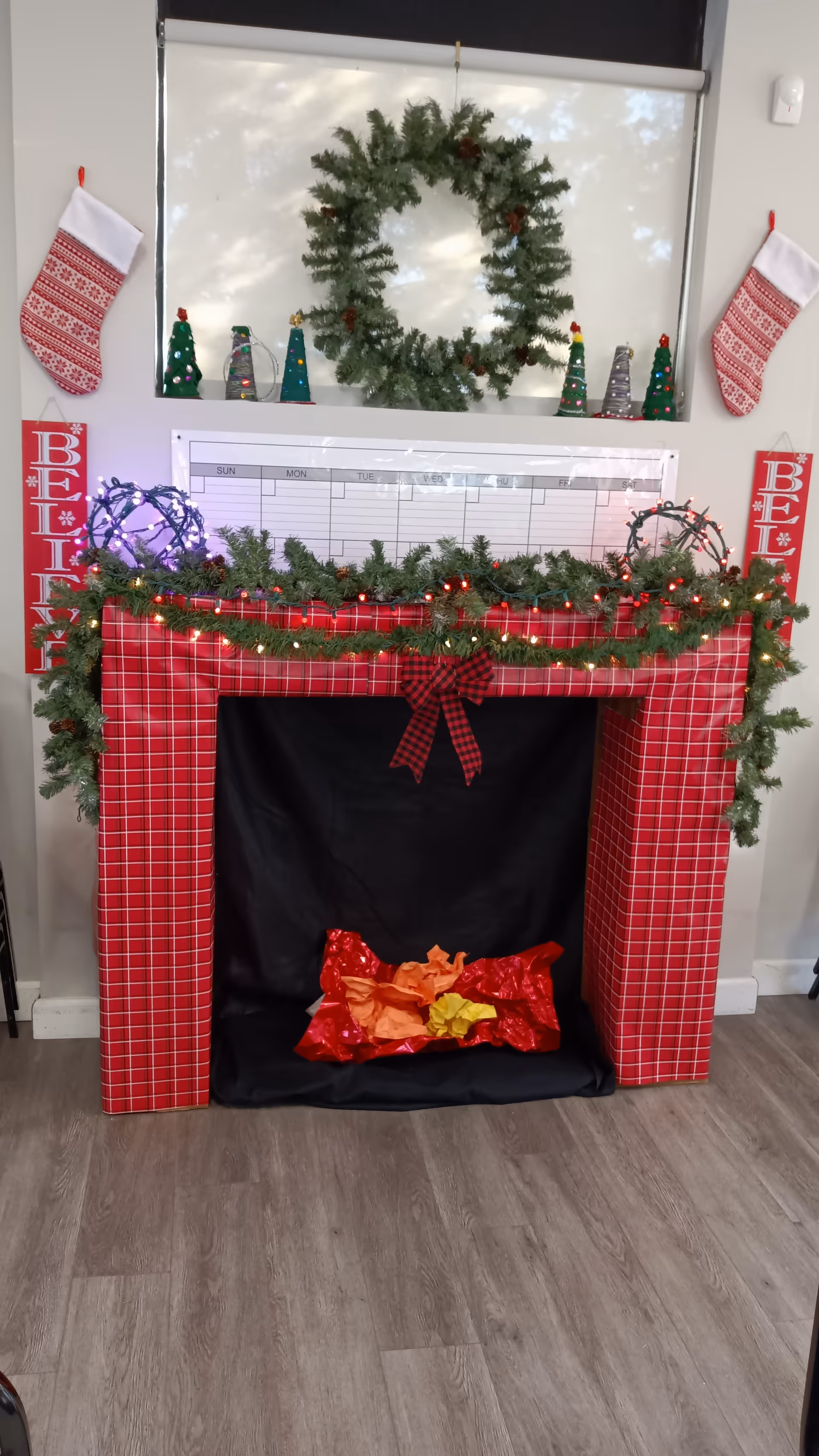 Festive mantel with garland, wreath, stockings, and red checkered wrap in a senior living space.