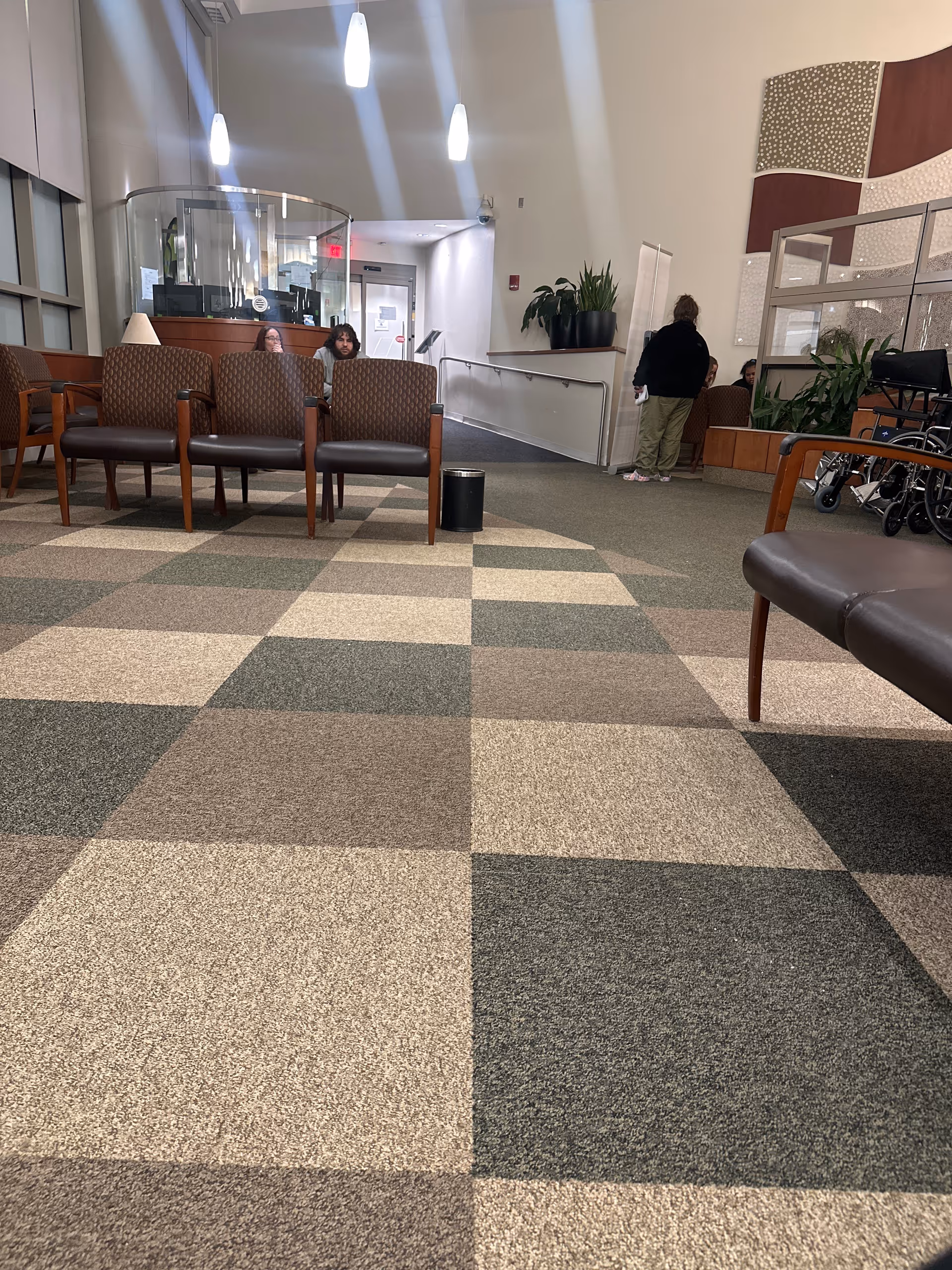 Middlesex Hospital waiting area with checkered carpet, chairs, and several seated people.