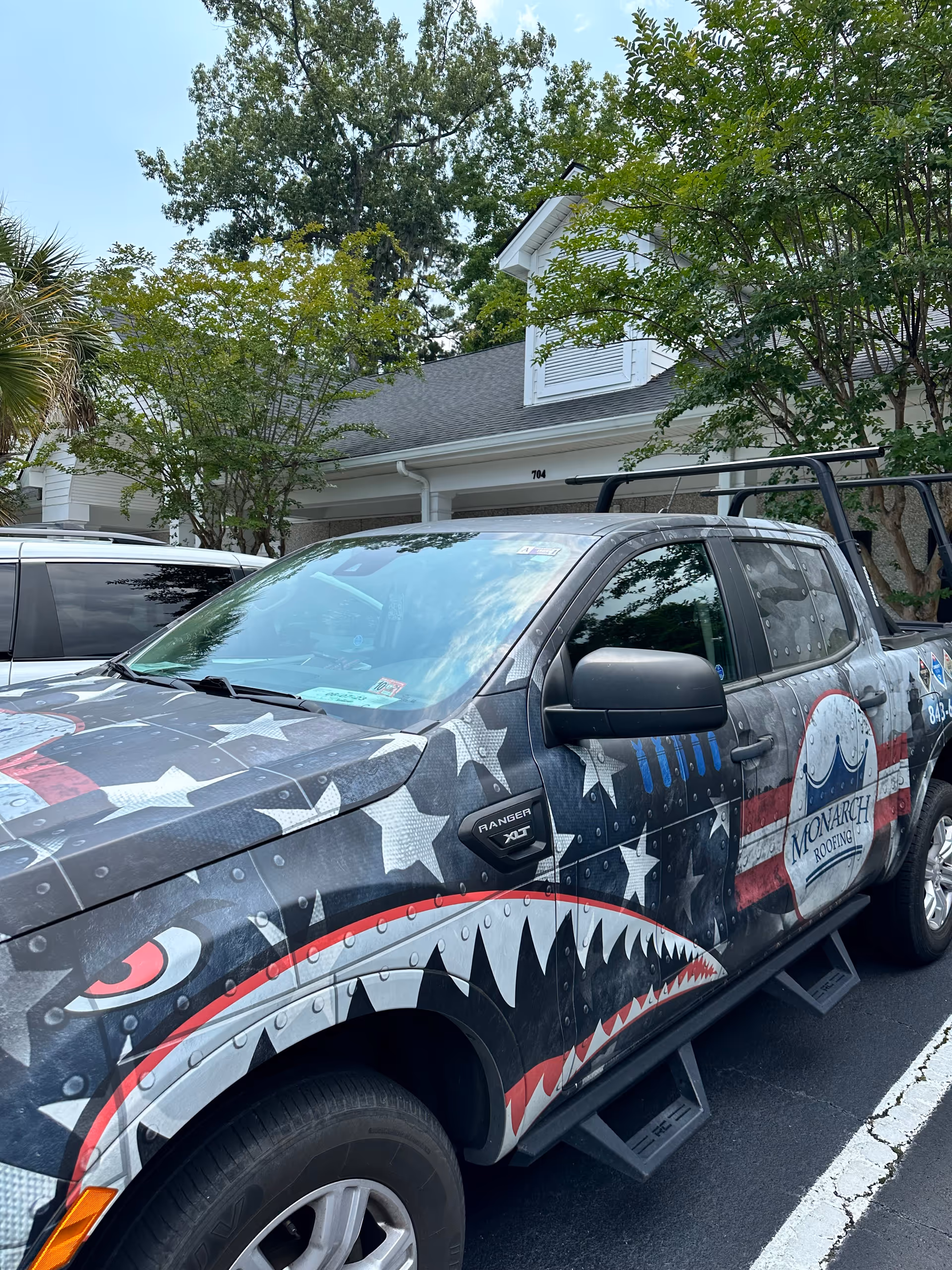 Exterior parking lot with a customized shark-teeth truck in front of a facility.