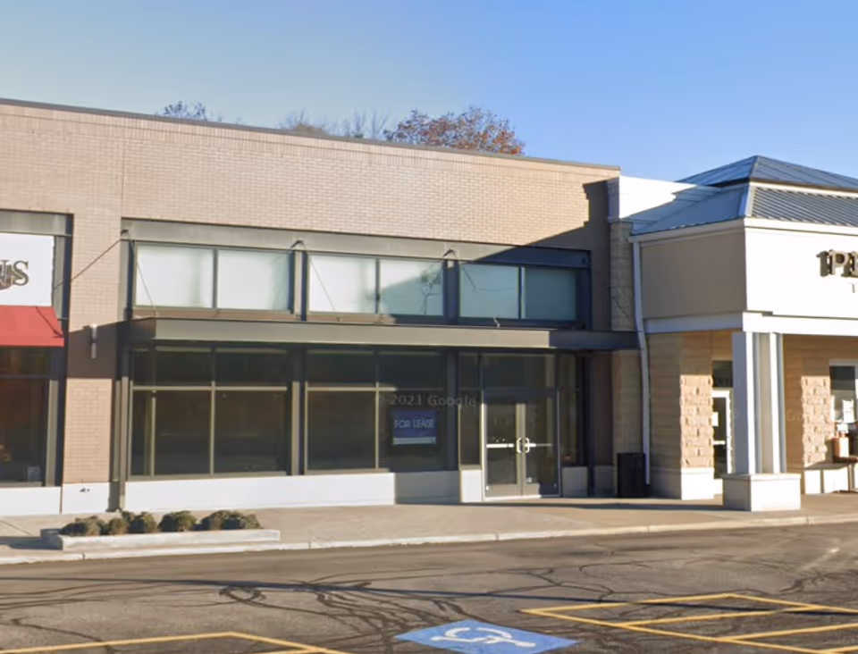 Exterior view of a strip mall with Home Instead storefront and large glass windows.