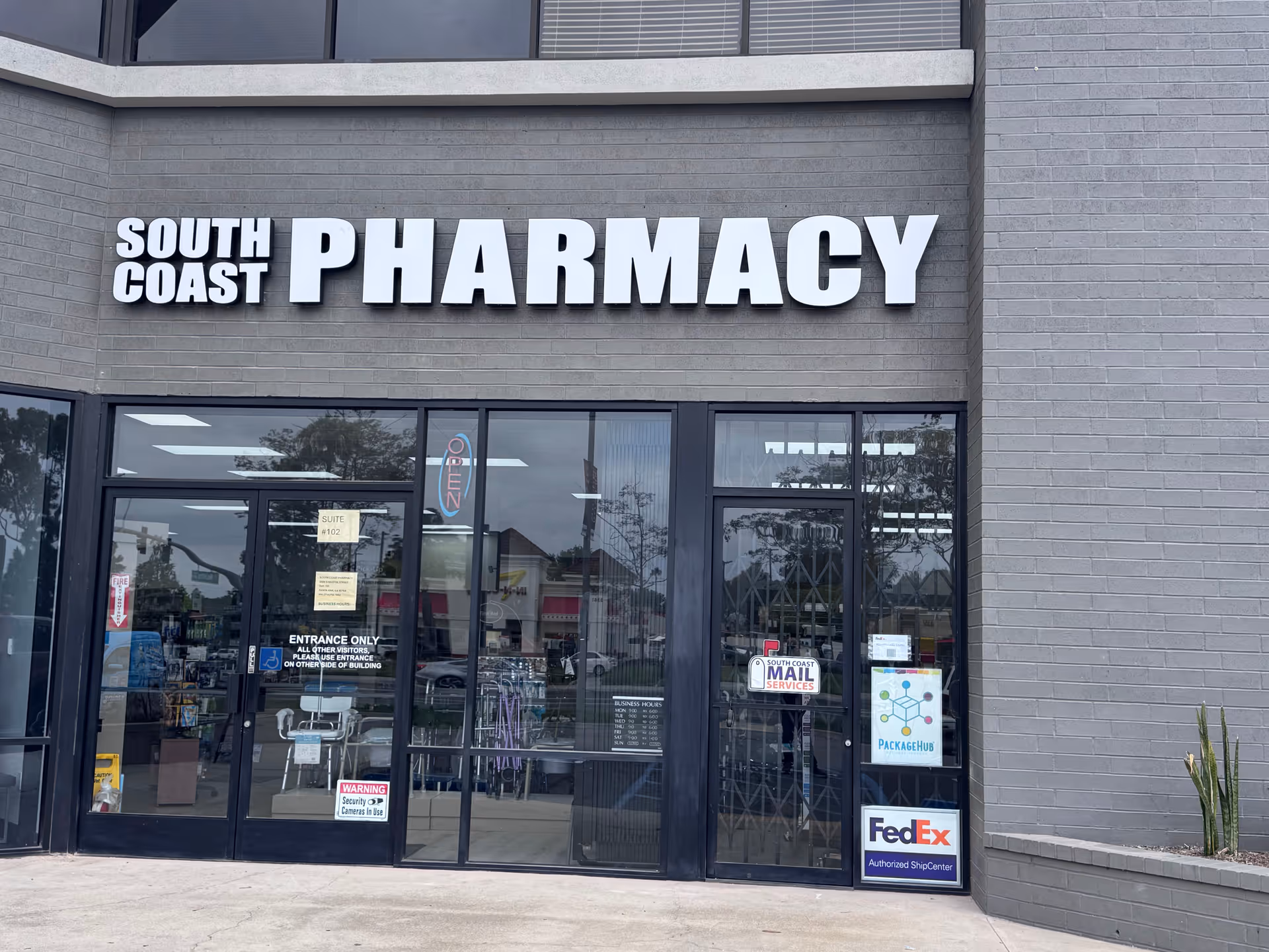 Exterior storefront of South Coast Pharmacy with large PHARMACY sign and glass doors