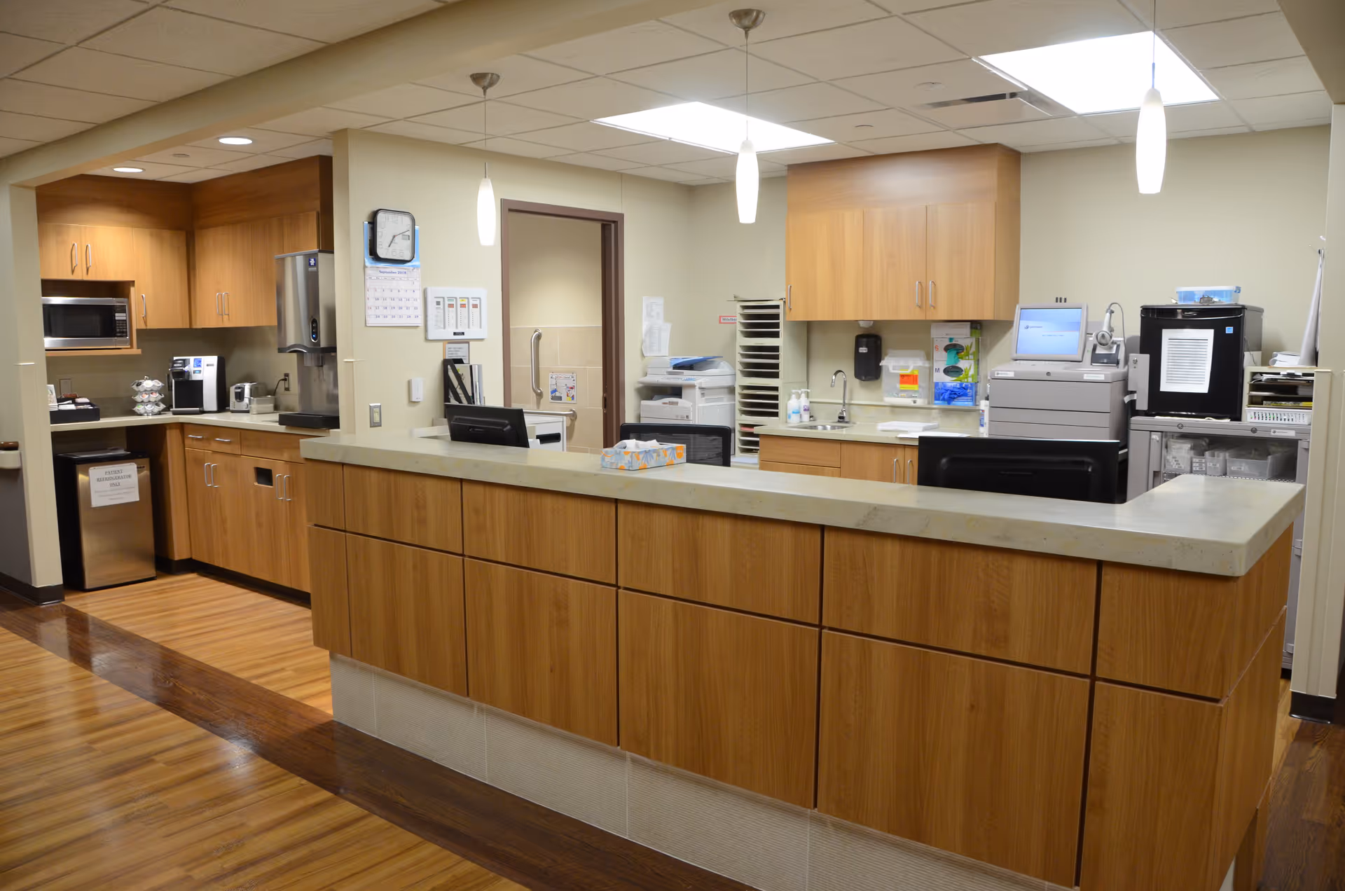 A spacious senior living facility kitchen with wooden cabinets, long counter, and appliances.