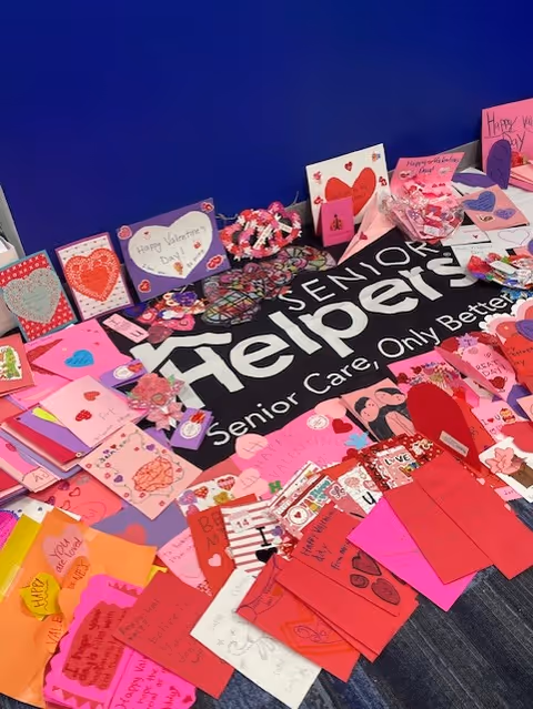 Colorful handmade cards scattered on the floor under a Senior Helpers banner.