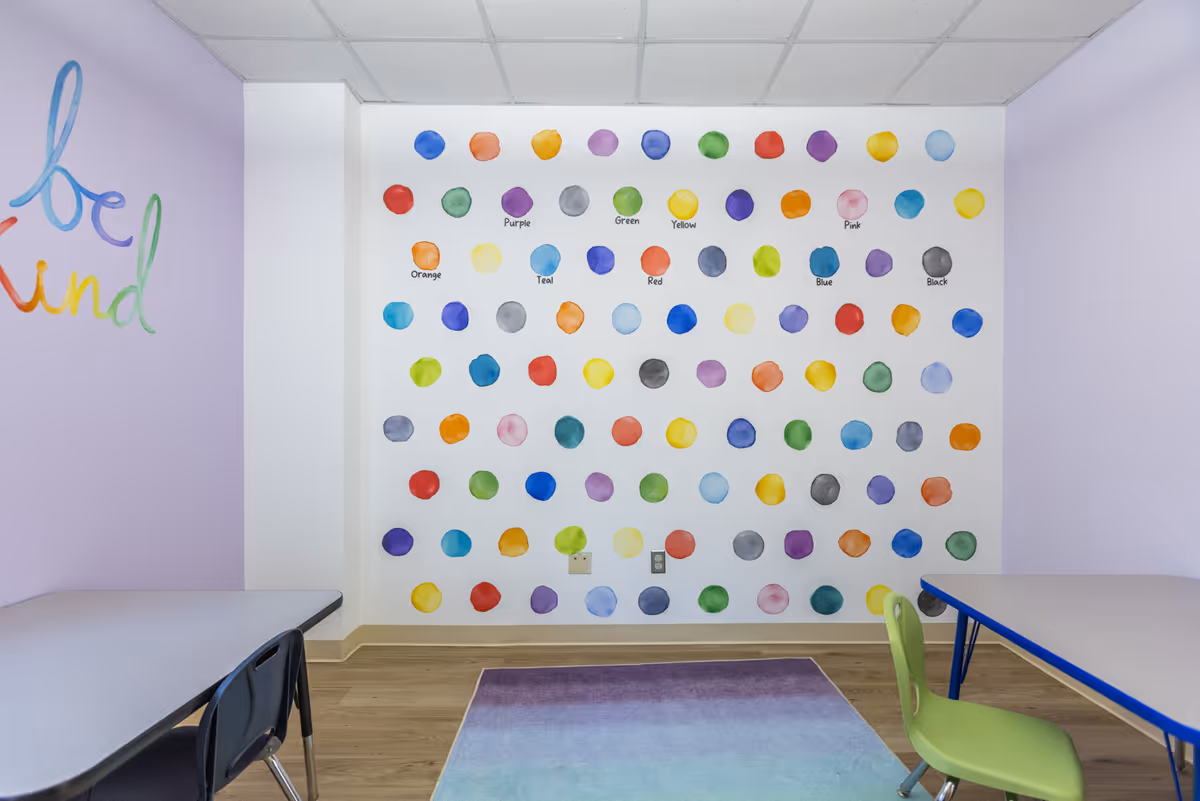 Colorful polka-dot wall decor in an activity room with tables and chairs.
