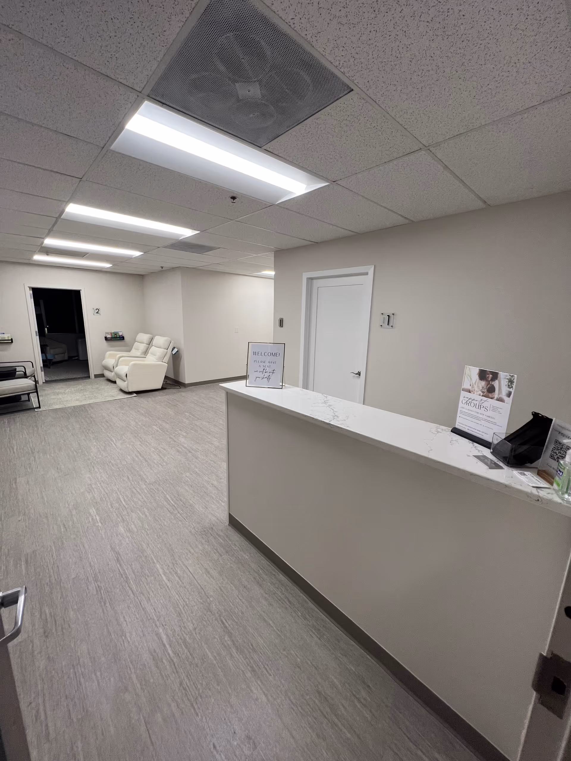 Bright, empty reception area with marble countertop desk and white seating in a senior facility lobby.