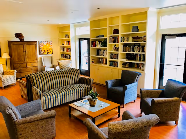 Cozy living room with striped sofa, armchairs, coffee table, and built-in bookshelves.