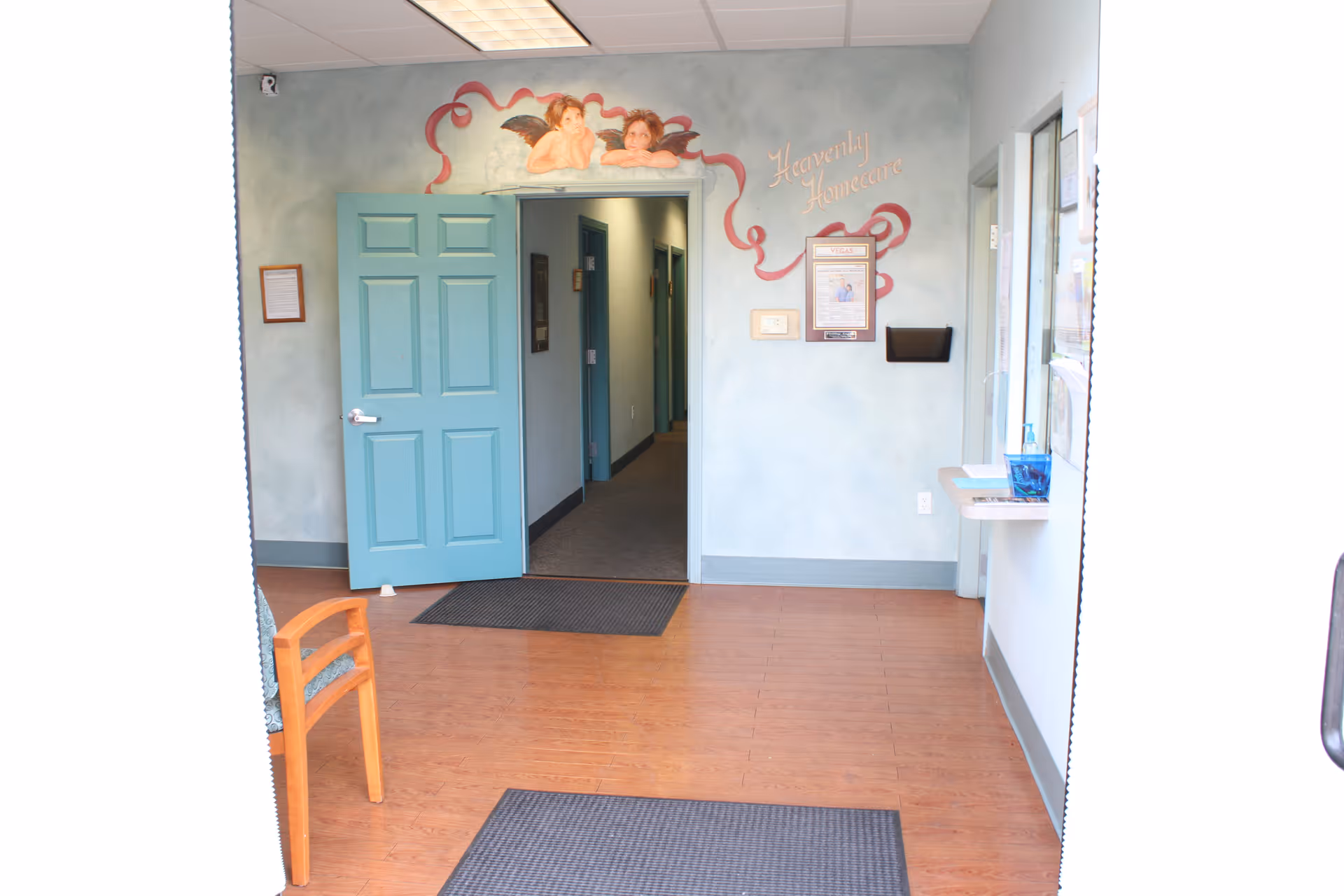 Open turquoise door leads into a hallway with pale blue walls and wall art.