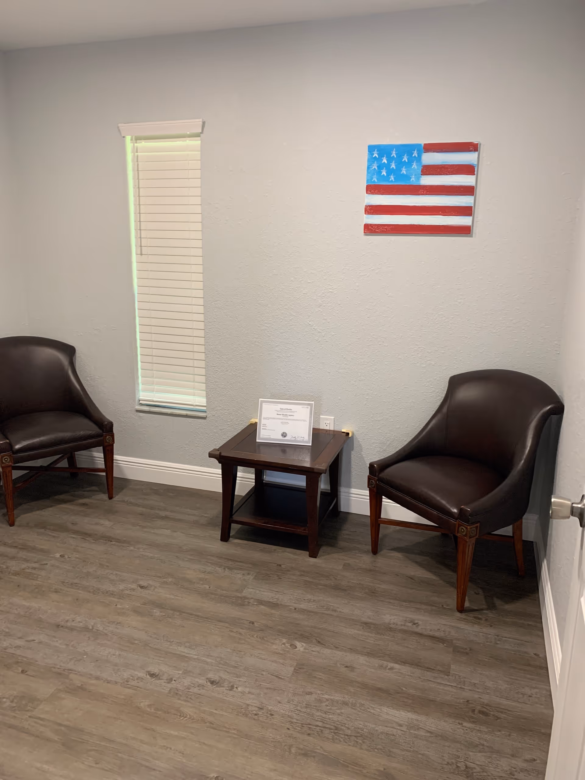 Two brown leather chairs flank a small wooden table in a quiet waiting area.