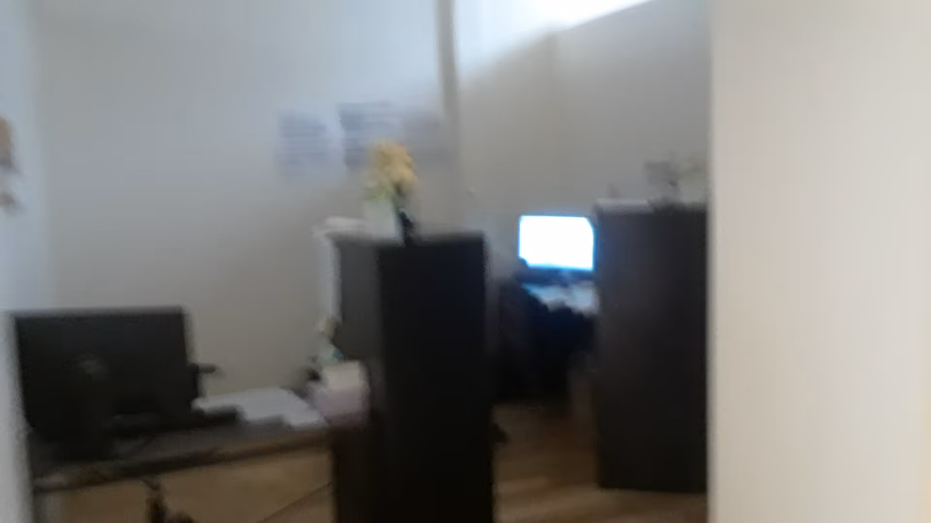 Blurry indoor office area with desks, computers, and filing cabinets.