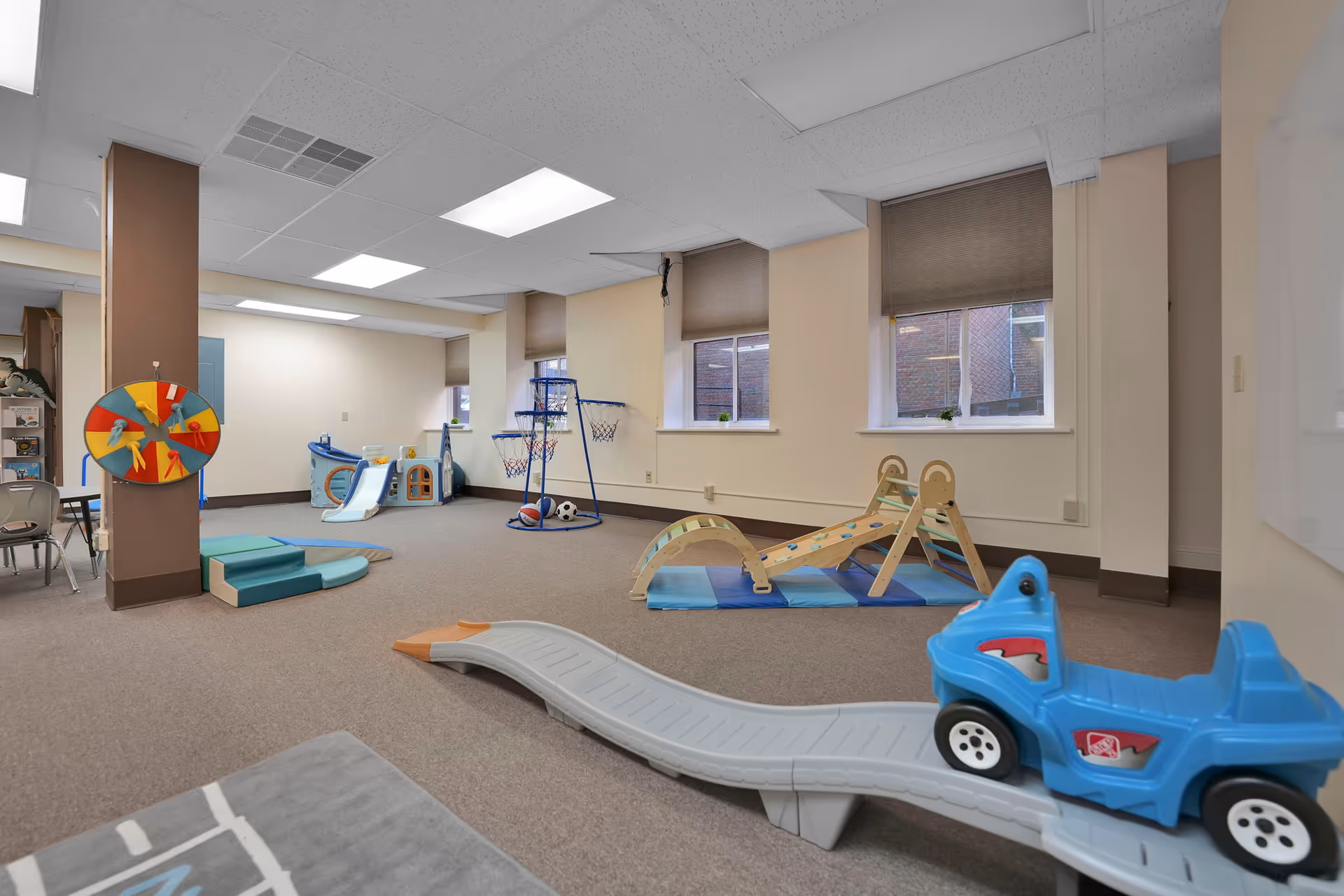 Indoor senior living facility playroom with colorful toys and climbing equipment.