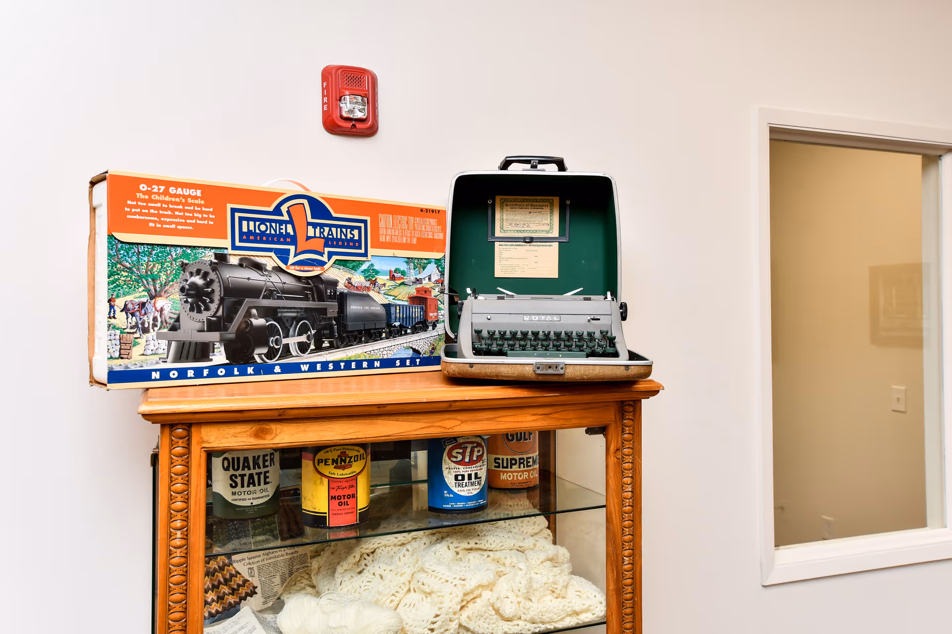 A vintage train set and typewriter rest on a wooden cabinet inside a senior care facility.