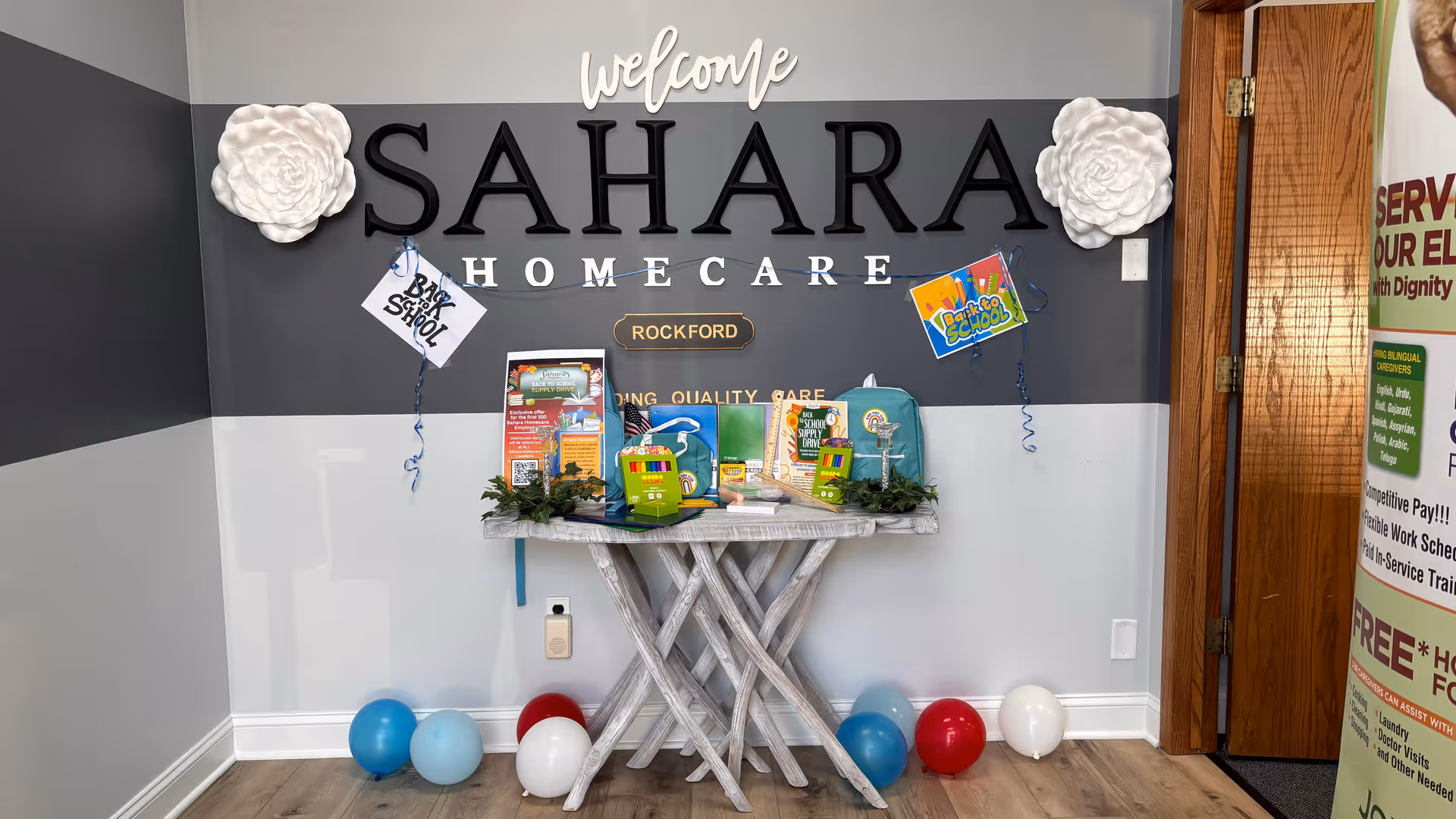 Interior lobby area with a welcome Sahara Homecare sign, table, and balloons.