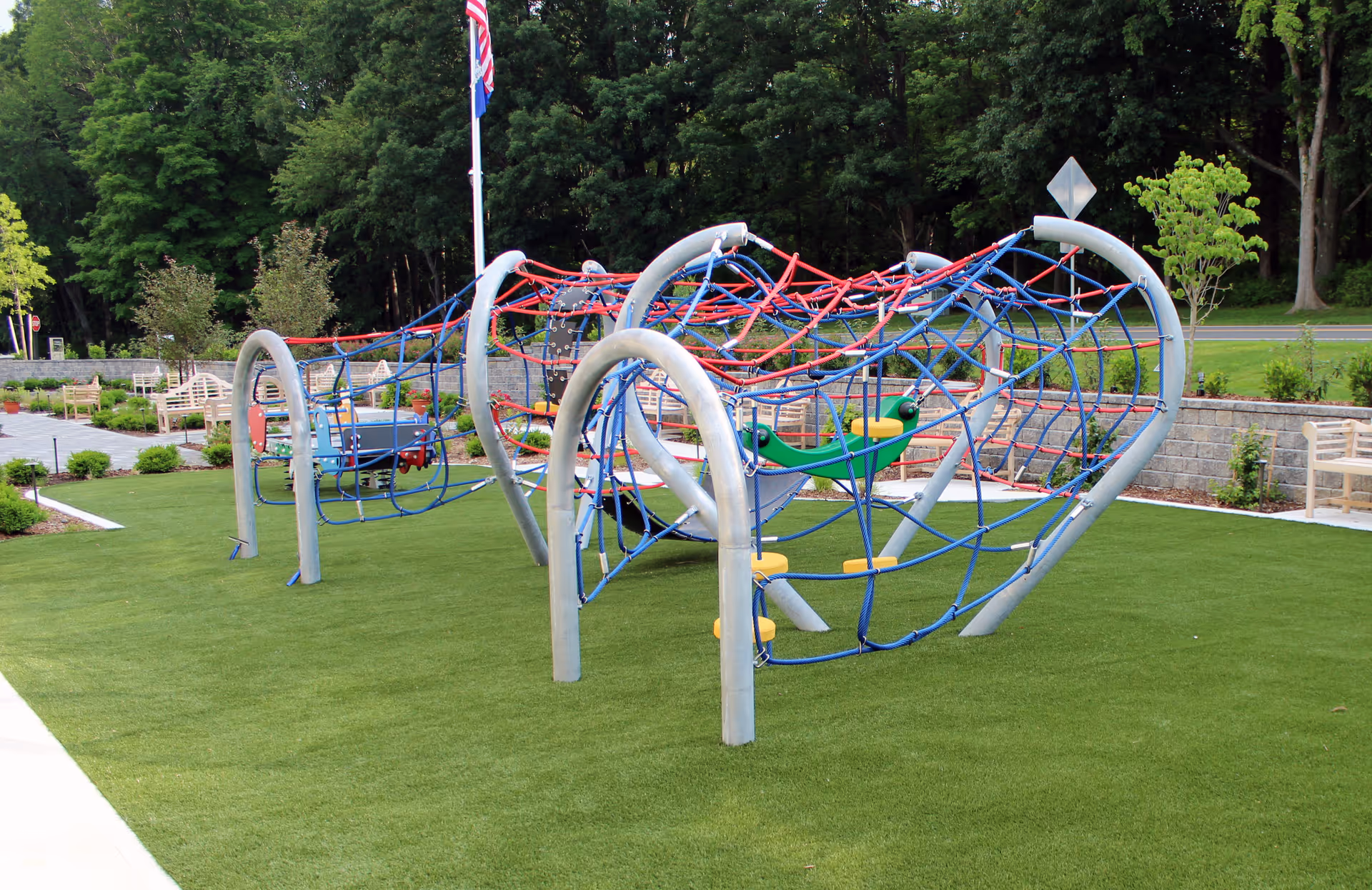 Outdoor playground with rope climbing nets on a grassy lawn at a hospice facility.