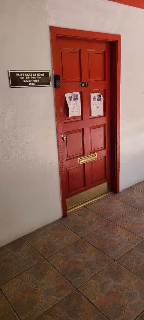 Red door with posted notices beside a plaque reading Elite Care At Home